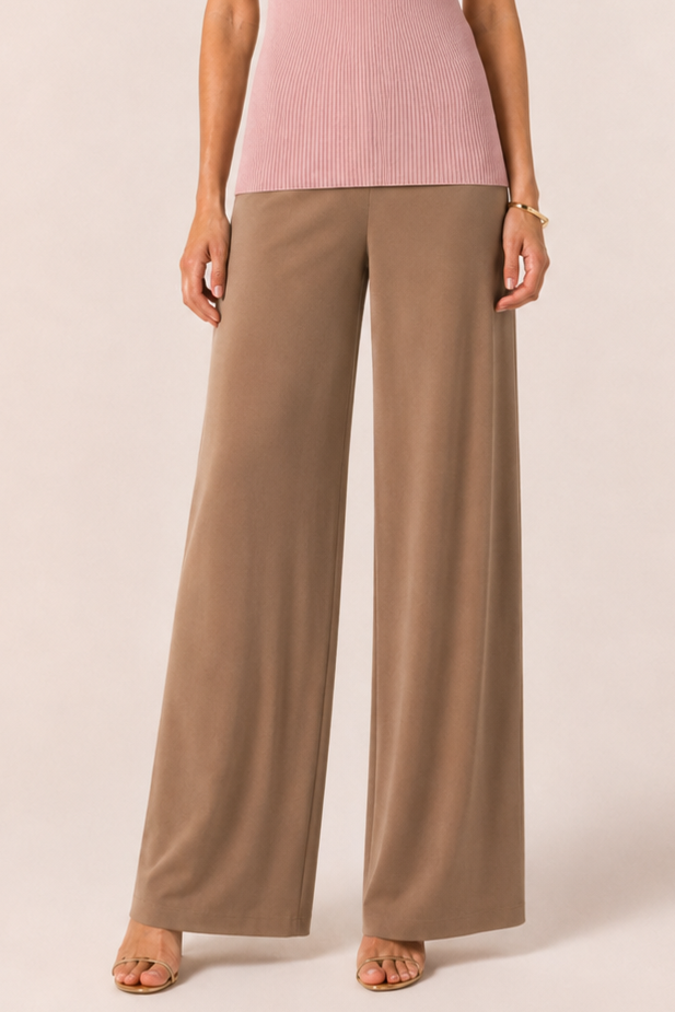 Woman wearing a pink top and beige pants on a white background