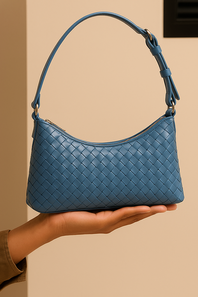 Blue woven handbag held in a hand against a beige background