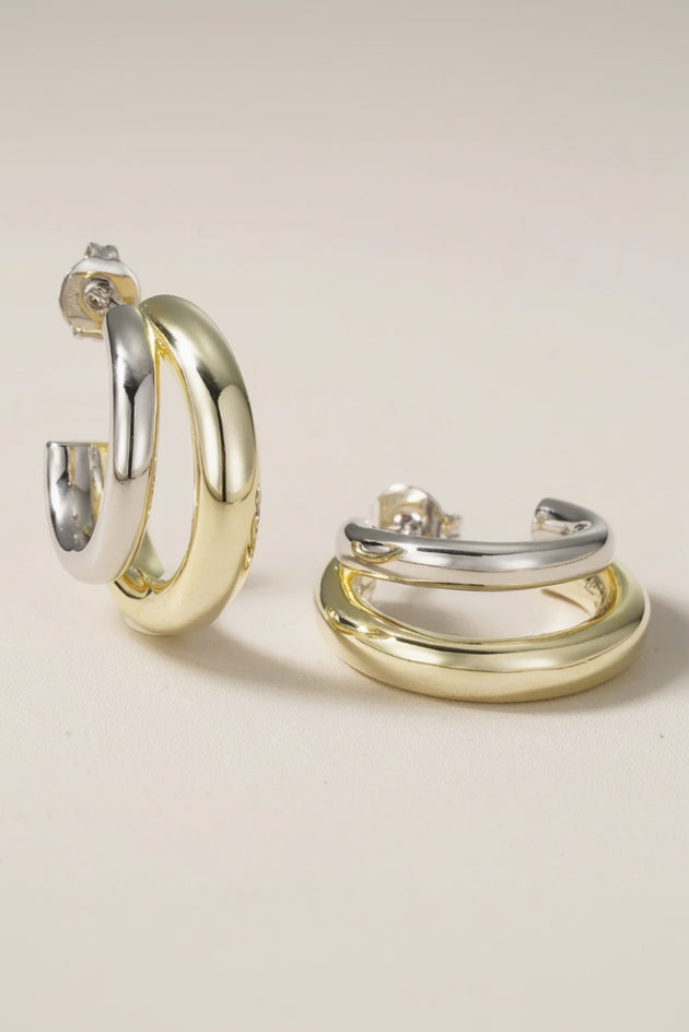 Pair of gold and silver hoop earrings on a beige background