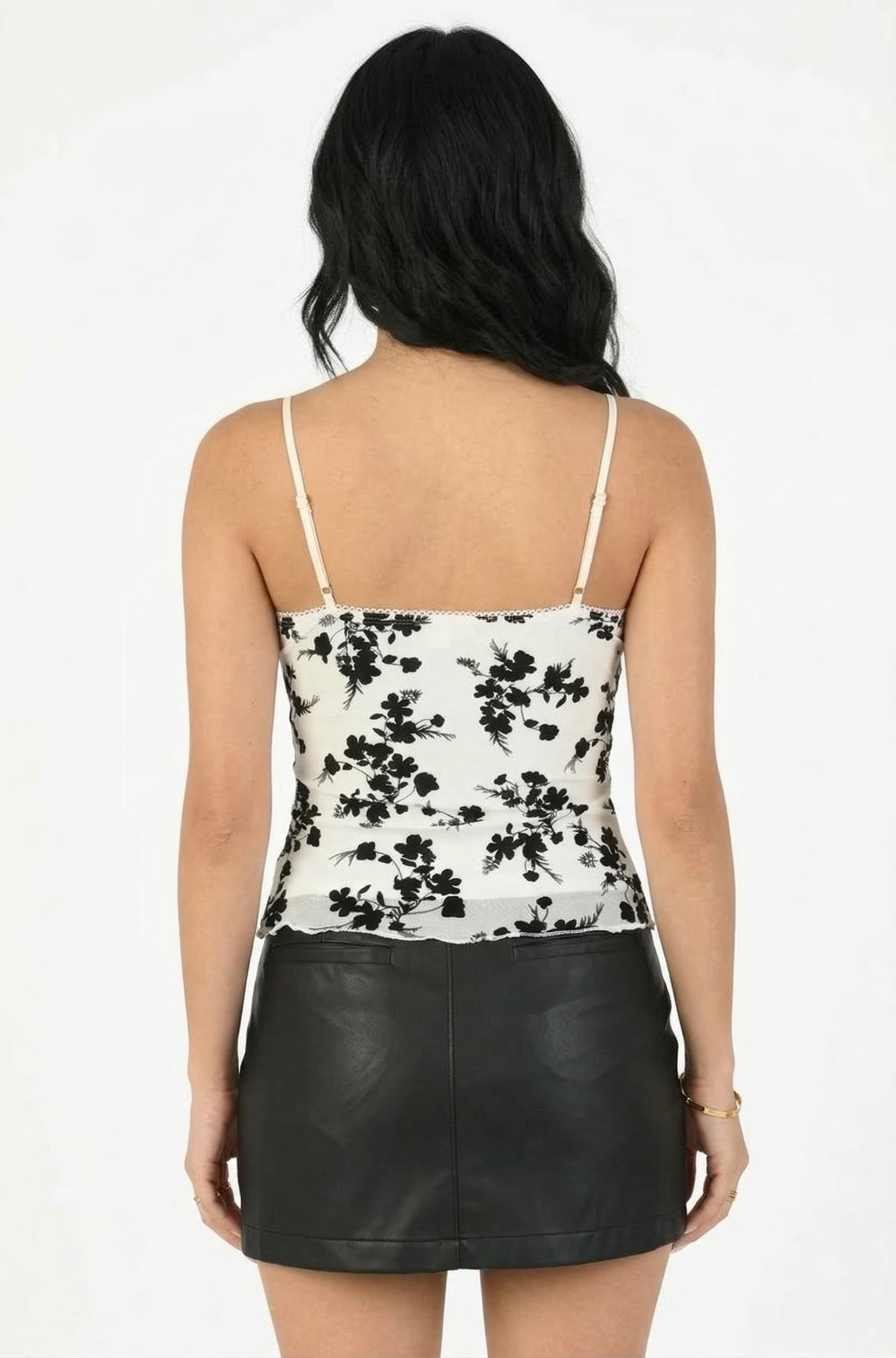 Woman wearing a floral top and black leather skirt on a white background