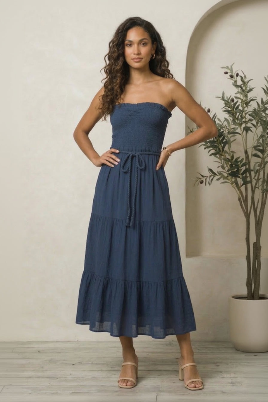 Woman wearing a blue strapless dress with a neutral background