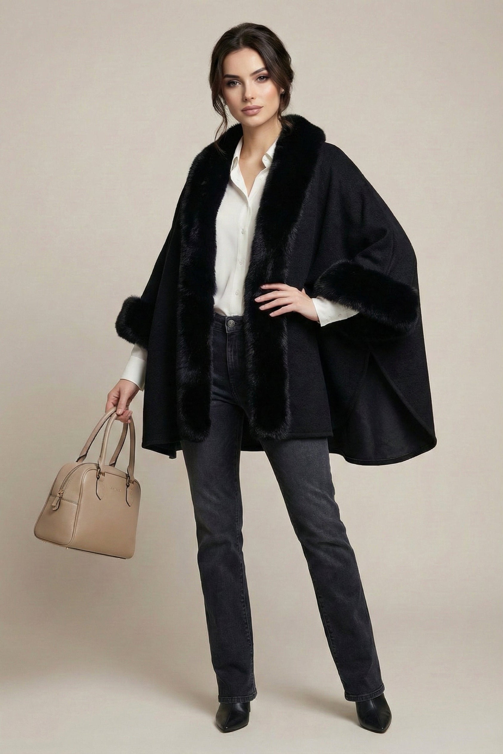 Woman wearing a black coat holding a beige handbag against a neutral background