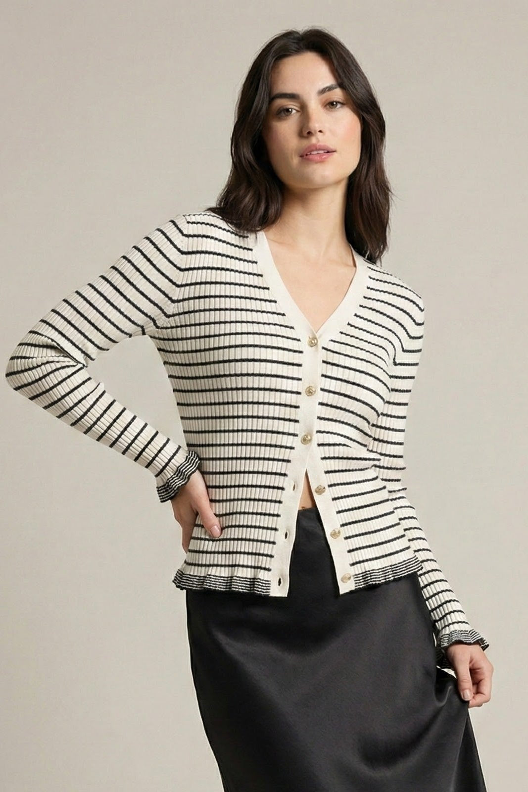 Woman wearing a striped cardigan and black skirt on a plain background