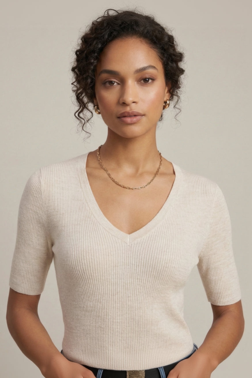 Woman wearing a beige ribbed sweater against a neutral background
