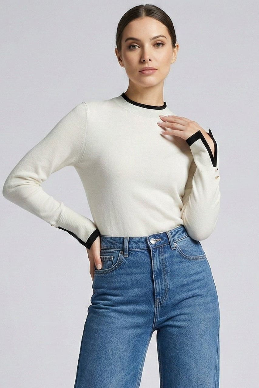 Woman wearing a white long-sleeve top and blue jeans on a light gray background