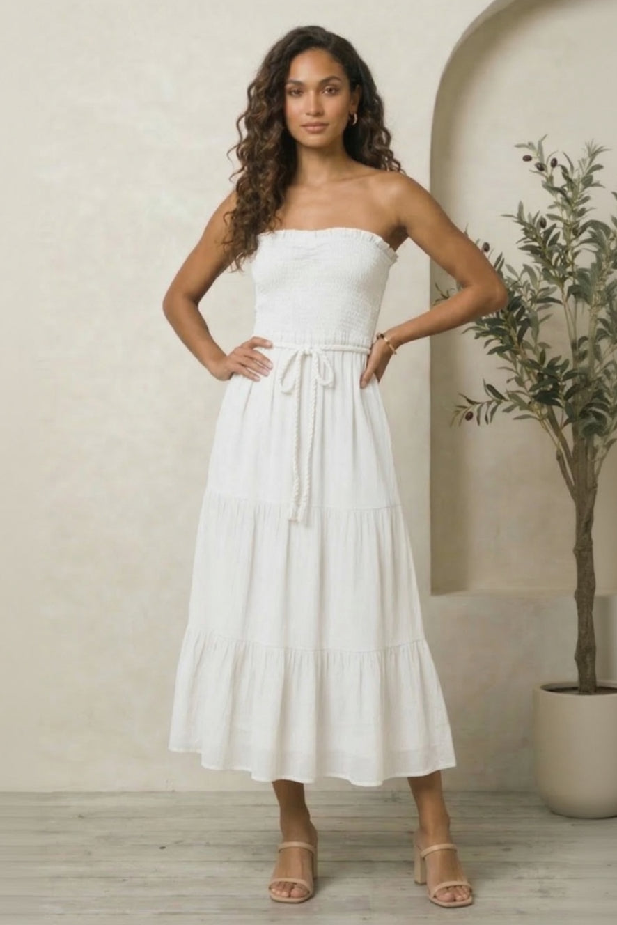Woman wearing a white strapless dress standing against a neutral background