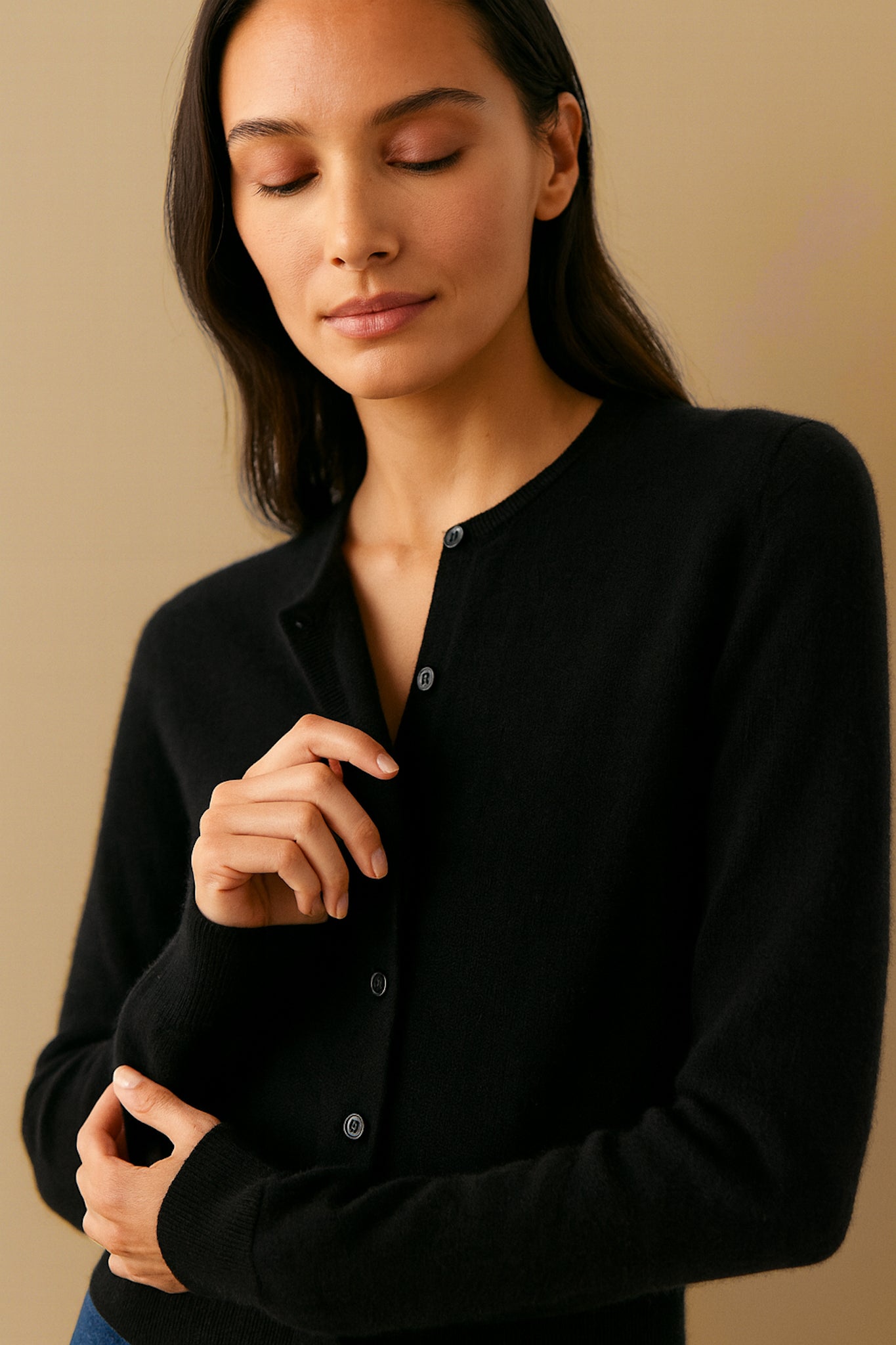 Woman wearing a black button-up shirt against a beige background