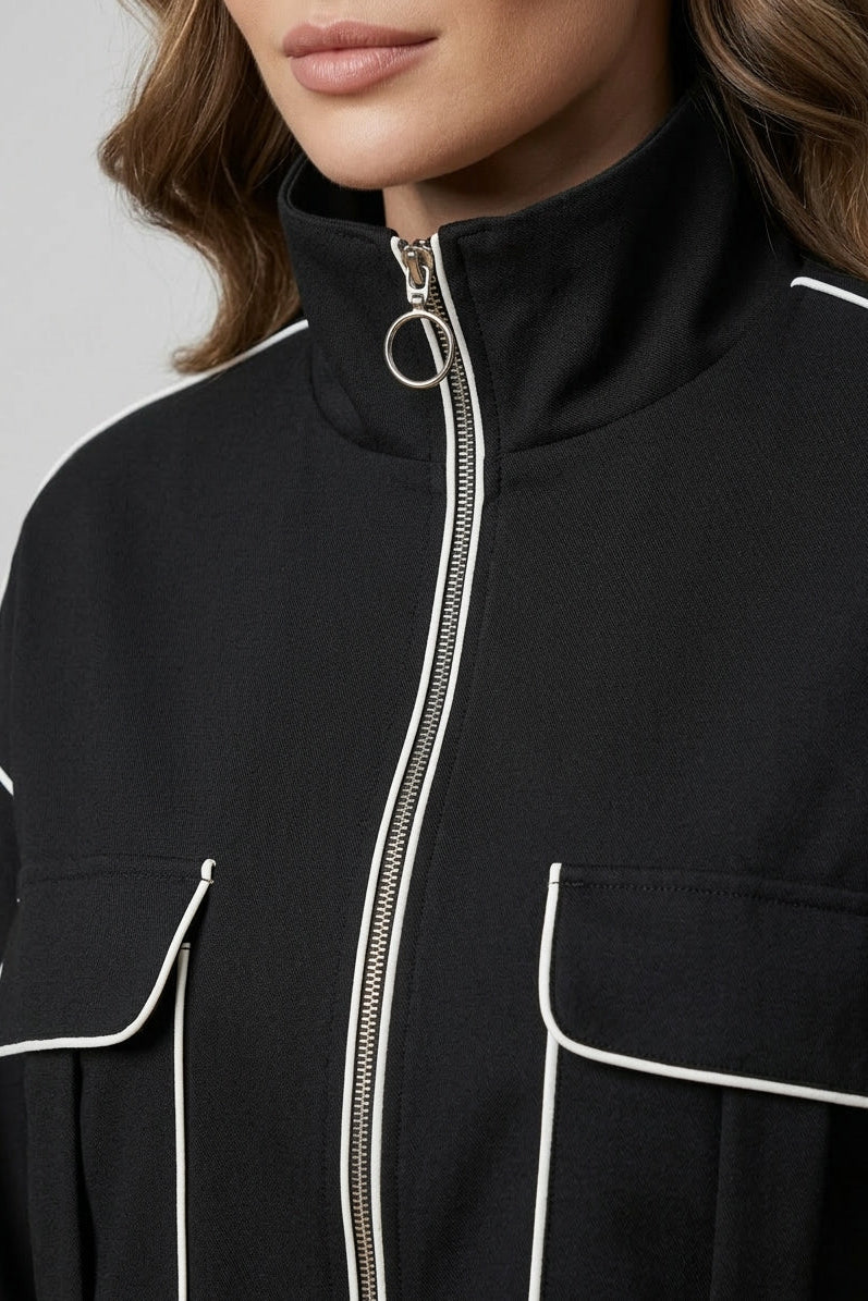 Close-up of a black jacket with white piping on a plain background
