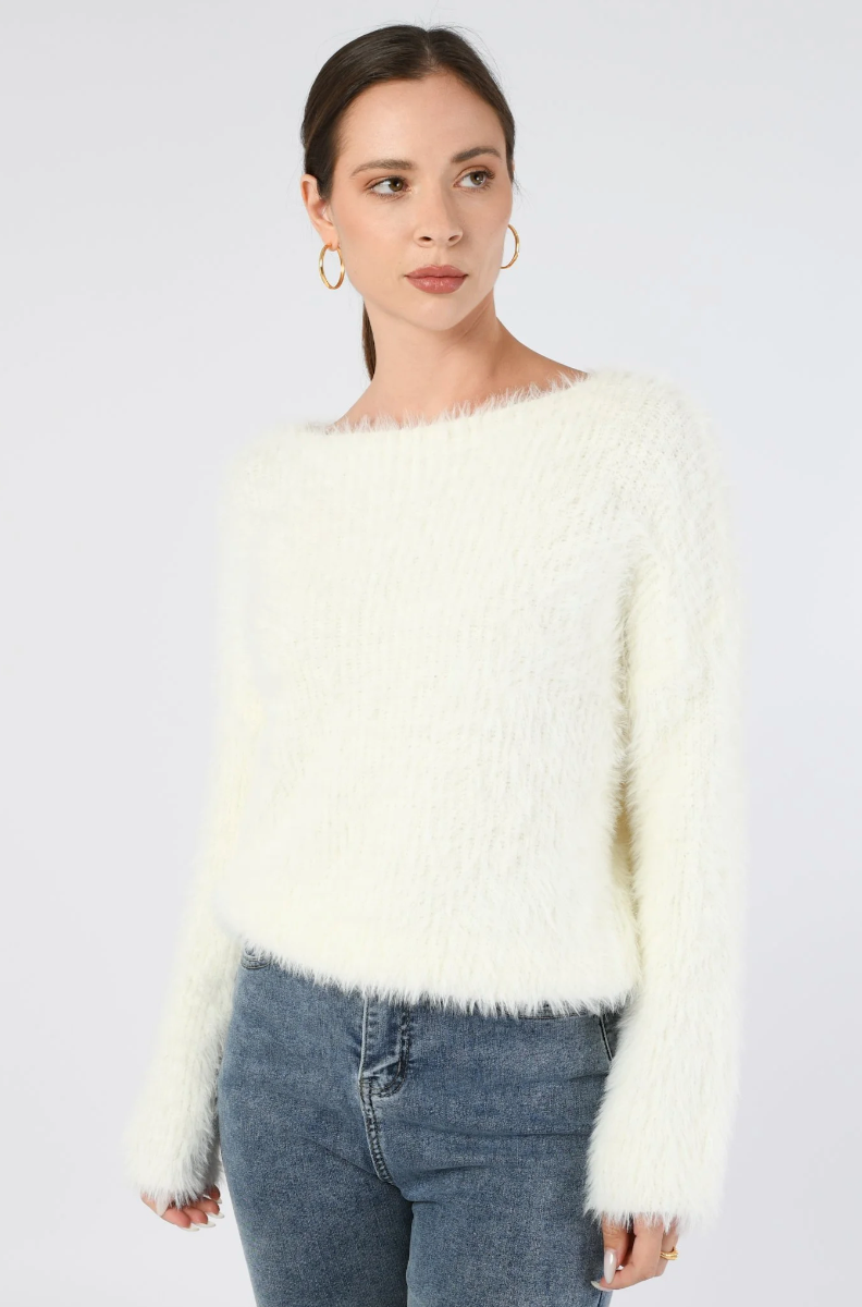 Woman wearing a fluffy white sweater and jeans on a plain background