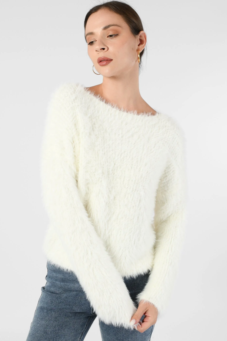 Woman wearing a white fluffy sweater against a plain background