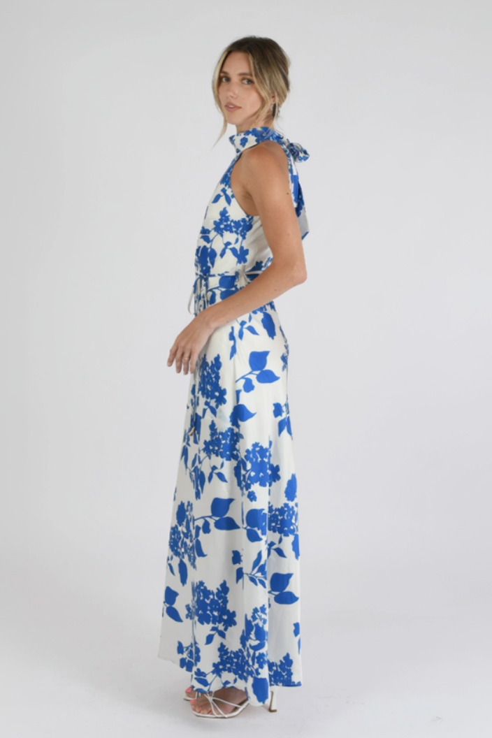 Woman wearing a white dress with blue floral pattern on a plain background