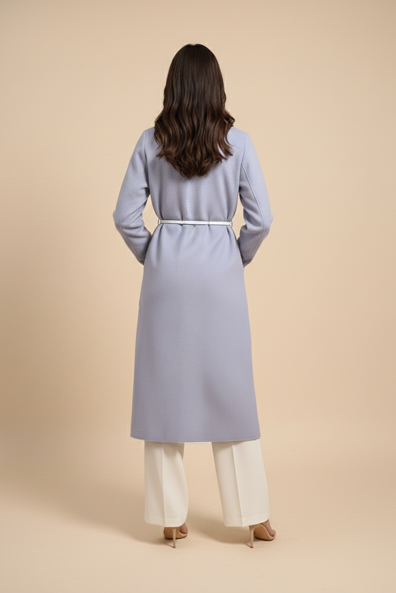 Woman wearing a long light gray coat on a beige background